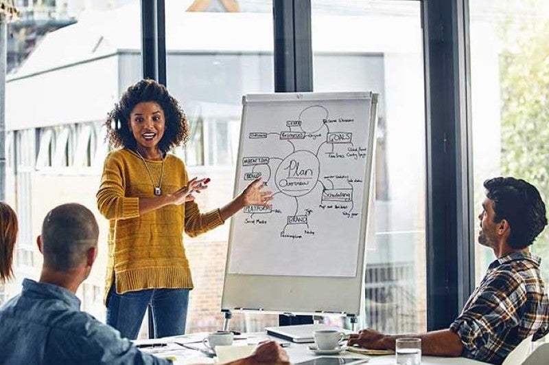 oman Educator Standing in Front of Whiteboard surrounded by Students